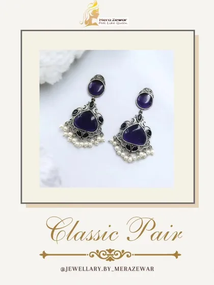 This classic pair of dangle earrings features a deep purple stone with a silver oxidized setting and delicate pearl accents. It's an elegant choice for any occasion.