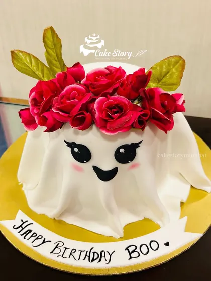 A spooky but cute ghost cake for a 'Happy Birthday Boo'. The ghost is draped in white fondant and wears a crown of red roses, making it a fun Halloween or themed birthday cake.