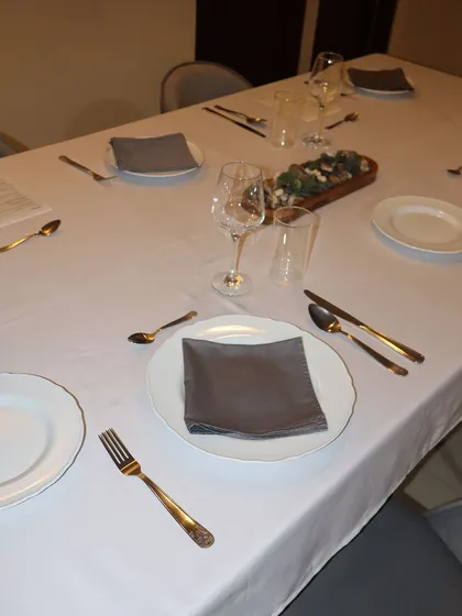 Every place setting is thoughtfully arranged to create a sense of occasion. The combination of classic white linens and modern tableware sets the stage for a sophisticated meal.