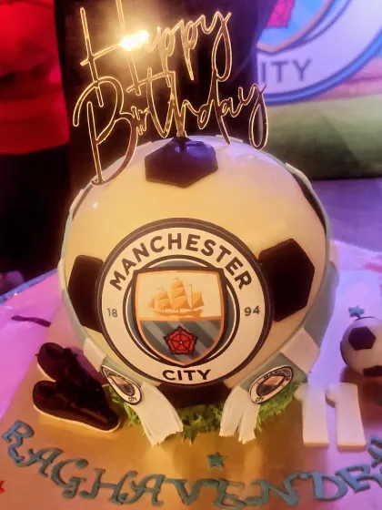 The amazing Manchester City themed cake, shaped like a football with the team's crest. A custom cake is the perfect centerpiece for a themed party.
