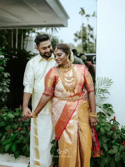 The couple holding hands, sharing a look of love and happiness. The bride's rich saree and gold jewelry are stunning.