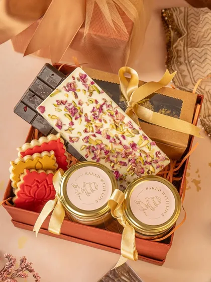An open gift box revealing a curated selection of treats. This shot gives a peek inside the hamper, showcasing the variety and quality of the products, from artisanal chocolate bars to custom cookies.