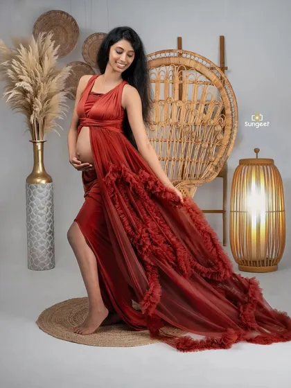 A dynamic pose that highlights the flowing train and elegant design of this red maternity gown.