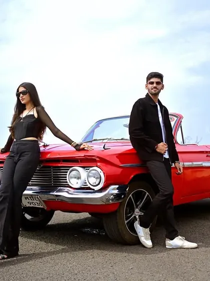 A stylish portrait of the couple posing with their vintage red car. This shot has a cool, editorial feel, perfect for a pre-wedding album cover.