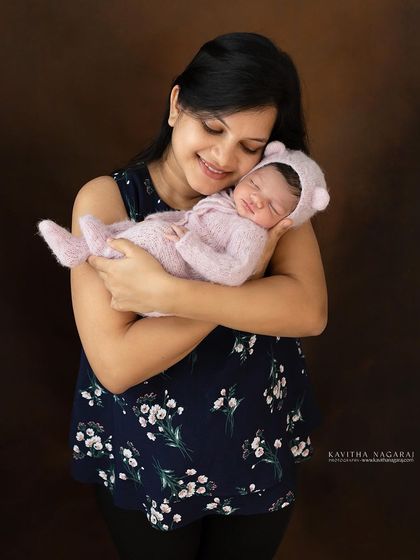 A mother holds her newborn baby, both dressed in soft, cozy outfits. This portrait captures the warmth and comfort of a mother's love.