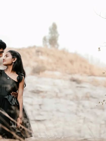 A romantic portrait of a couple in a dry, grassy field. The soft, muted tones of the landscape create a dreamy and intimate atmosphere.