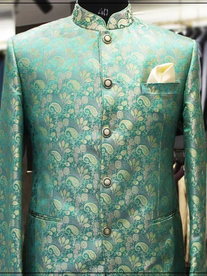 A close-up of the sea-green and gold paisley bandhgala, showing the shimmer and detail of the brocade fabric.
