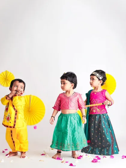 A playful Janmashtami scene with three children in traditional attire. Our studio can accommodate small groups of siblings or friends for festive sessions.