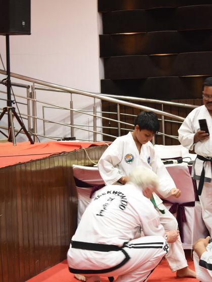 An instructor corrects a young student's form during a seminar, highlighting the importance of personalized guidance.