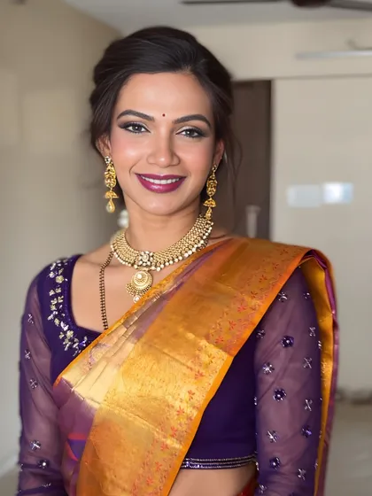 I love playing with color to complement traditional attire. This South Indian bridal makeup features a beautiful berry lip and shimmering eyeshadow that perfectly matches the tones in her purple and gold silk saree, creating a harmonious and elegant look.