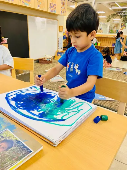 Using chunky crayons, this child explores color mixing and layering on a large canvas. This mark-making activity builds shoulder and arm strength, which is a crucial precursor to the fine motor control needed for writing.