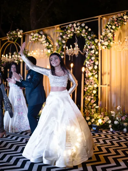 A bridesmaid having fun at the sangeet. Her ivory lehenga with a full-sleeved blouse is a chic and modern choice that is both stylish and comfortable for dancing the night away.