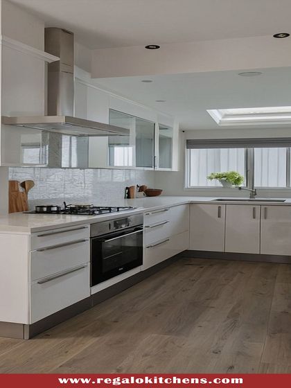 This L-shaped kitchen with a parallel counter is finished in high-gloss white, creating a clean and modern look. The wooden floor adds warmth, and the layout is perfect for efficient movement while cooking.