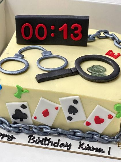 A mysterious and fun detective-themed cake. It's decorated with handcuffs, playing cards, a magnifying glass, and a countdown clock, perfect for an escape room fan.