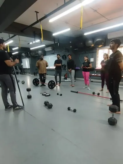 A master trainer demonstrates correct form while students observe. Practical classes like this, focusing on weightlifting and equipment use, are a core part of our curriculum.
