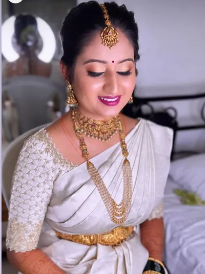 A bride in a simple off-white saree. Her custom blouse features a delicate net pattern embroidery, adding a touch of modern sophistication.