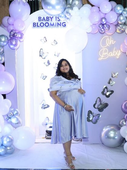 The glowing mom-to-be at her 'Baby is Blooming' shower. The soft lavender dress perfectly complements the butterfly-themed decor.