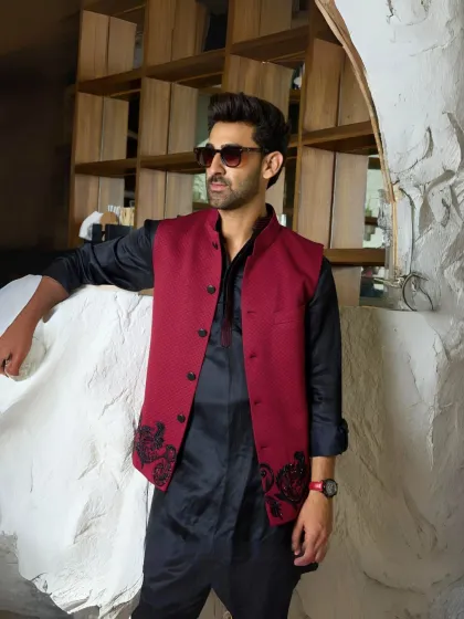 Refined elegance, reimagined. The black silk kurta paired with a tailored maroon waistcoat offers a perfect blend of structure and luxury for the wedding season.