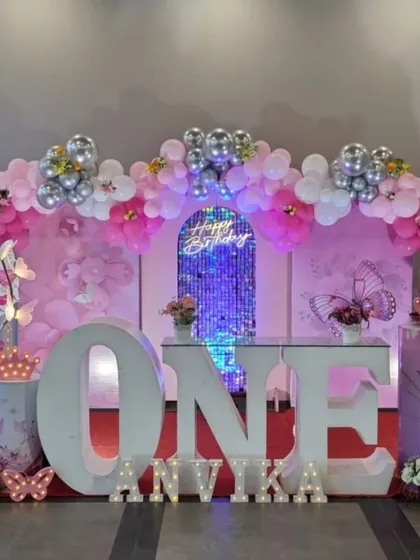 The main stage for the butterfly-themed first birthday, with a large 'ONE' table, a shimmer backdrop, and butterfly wing props.