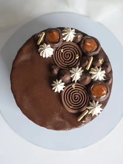 A top-down view of the Chocolate Caramel cake, highlighting the intricate decorations. The combination of dark chocolate and sweet, salty caramel is a classic for a reason.