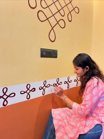 A closer look at the process of painting the intricate rangoli border. I use a fine brush to ensure each loop and curve is precise, creating a seamless pattern along the wall.