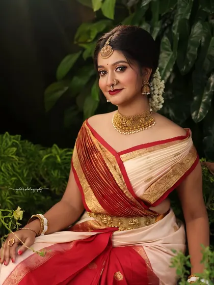 A classic seated portrait surrounded by lush greenery. The lighting is soft and flattering, highlighting the bride's features.
