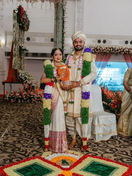 The couple stands together during their wedding ceremony. This full-length shot shows how the groom's custom sherwani and dhoti combination creates a cohesive and elegant look from head to toe.