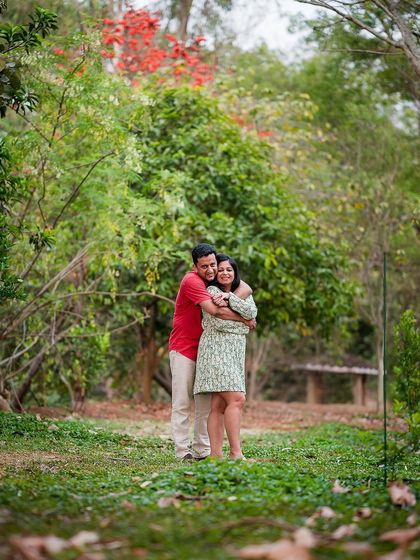 A couple shares a warm hug in a lush, green park. Our outdoor sessions use natural scenery to create a beautiful backdrop for your love story.