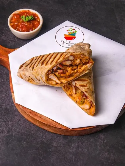 A grilled chicken wrap, cut in half and served on a wooden board with a side of salsa. The dark, rustic background is perfect for showcasing wraps, burritos, and rolls.