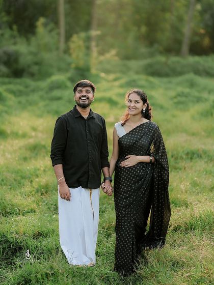 A classic portrait in a sun-drenched green field. The couple's traditional attire looks stunning against the natural backdrop.
