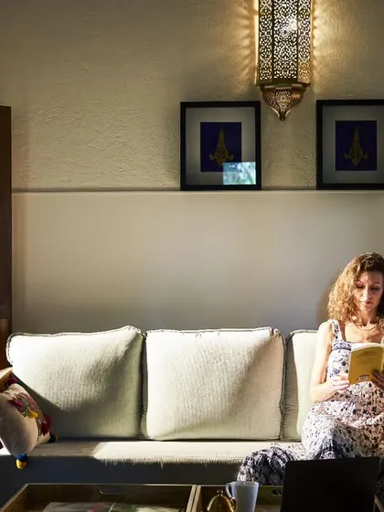 Lost in a good book, a guest relaxes on a sofa in her heritage room. These moments of quiet solitude are just as important as the scheduled therapies, allowing the mind to rest and integrate the day's healing.