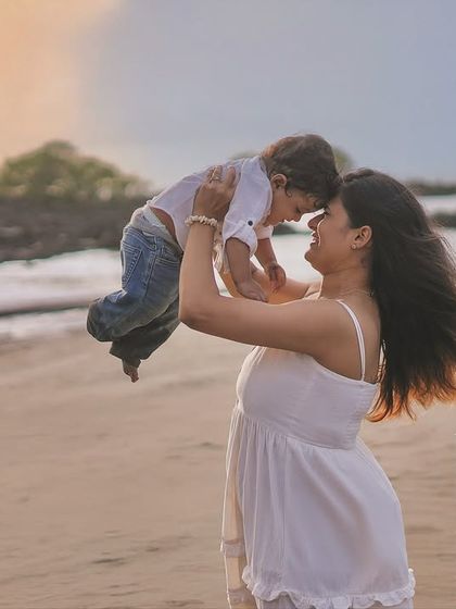 Flying high above the waves in his mother's arms. This dynamic and joyful shot captures a moment of pure bliss and trust between a mother and her child during their beach photoshoot.