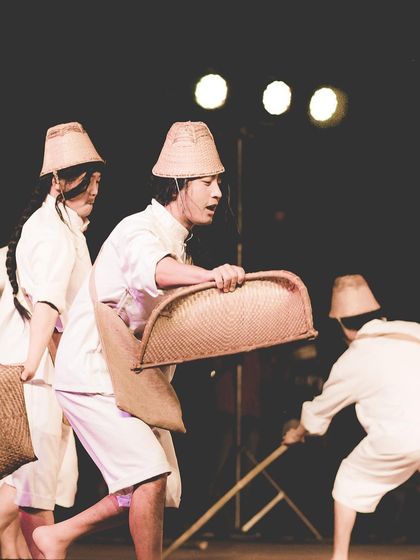 Performers in motion during a folk dance, carrying woven baskets. The photo captures the dynamic movement and storytelling inherent in the performance.