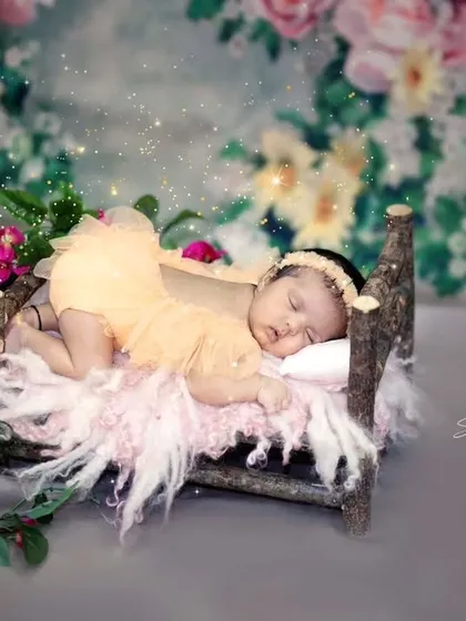 A little angel sleeping in a magical garden. This newborn portrait uses a miniature rustic bed and sparkling lights to create a dreamy, fairytale atmosphere.