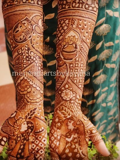 This full-arm view showcases how storytelling elements are integrated into the complete bridal mehendi. The design flows from the couple's portraits on the palms to kalash and lotus motifs on the arms.