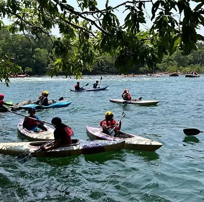 A fleet of kayaks from our summer camp explores a calm section of the Kali River, surrounded by dense forest.