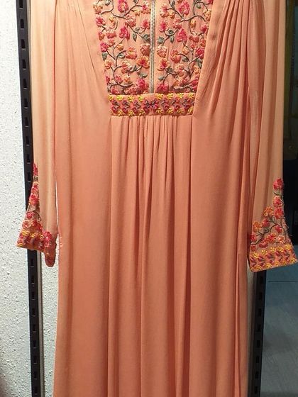 This peach-colored dress features beautiful floral embroidery around the neckline and cuffs. The relaxed fit and soft fabric make it a comfortable yet stylish choice for a festive gathering.