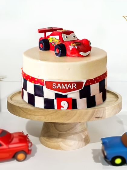 A high-speed Lightning McQueen cake for a 9th birthday. This design features the famous race car on a track-themed cake, ready for a fast and fun party.