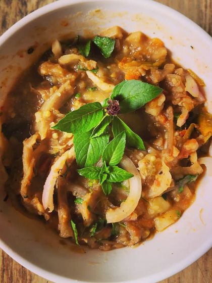 Eromba served in a white bowl, garnished with a fresh basil sprig. This dish is a staple in Manipuri cuisine and one of my personal favorites.
