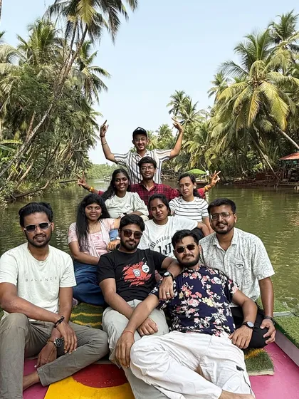 A fun group photo on the backwater boat in Honnavar, with coconut trees creating a perfect tropical backdrop.