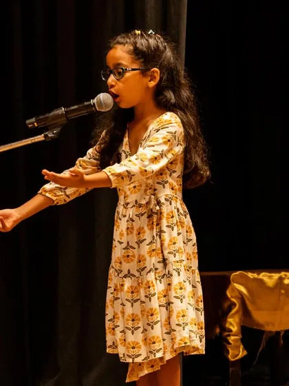 A solo performance at the microphone. This builds public speaking skills, teaching children how to use a microphone effectively and project their voice.