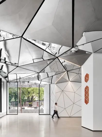 A person walking through the lobby provides a sense of scale, demonstrating how the architectural elements create a powerful human experience. The design connects the entrance to the core, guiding visitors through a visually rich environment.