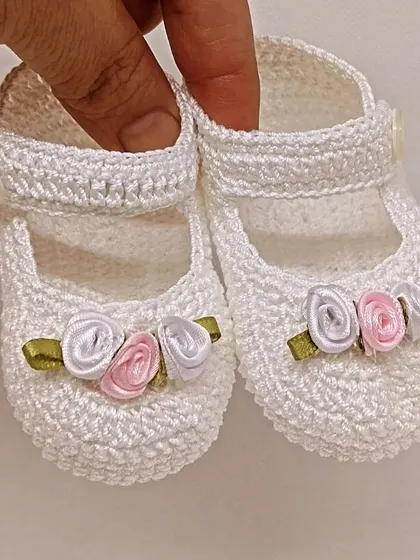These sweet white Mary Jane booties are decorated with tiny, handmade satin ribbon roses in pink and white, offering a subtle hint of color.