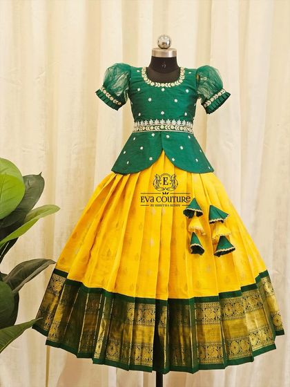 This yellow and green Pattu Pavadai is a classic choice for festive events. The green peplum blouse has delicate white embroidery and a matching belt.