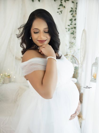 A soft and dreamy close-up portrait. The mother-to-be, dressed in white, has a serene expression, creating a truly angelic image.