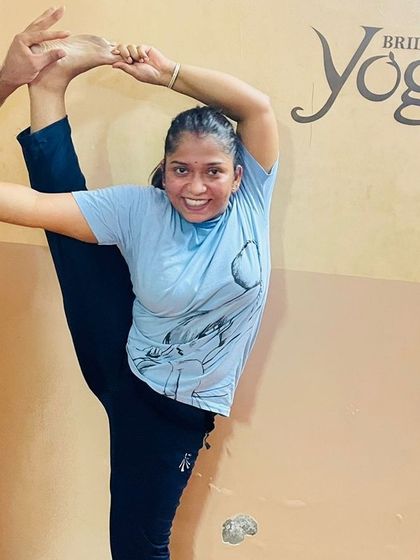 The smile of achievement. A student joyfully holds an advanced standing split with the help of an instructor, showcasing the progress that comes with dedicated practice and expert guidance in our classes.