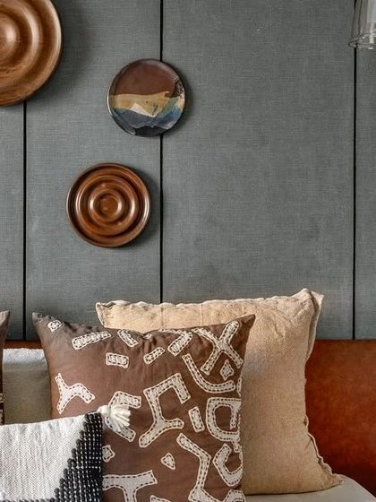 A close-up of the styling on the headboard wall. The collection of wooden plates adds an artistic, handcrafted element to the room's modern design.