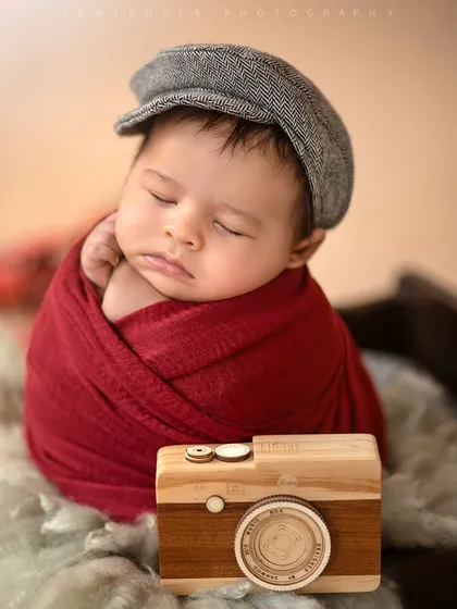 This detailed shot focuses on the tiny wooden camera prop next to the sleeping baby, adding a perfect touch to our little traveler's portrait.