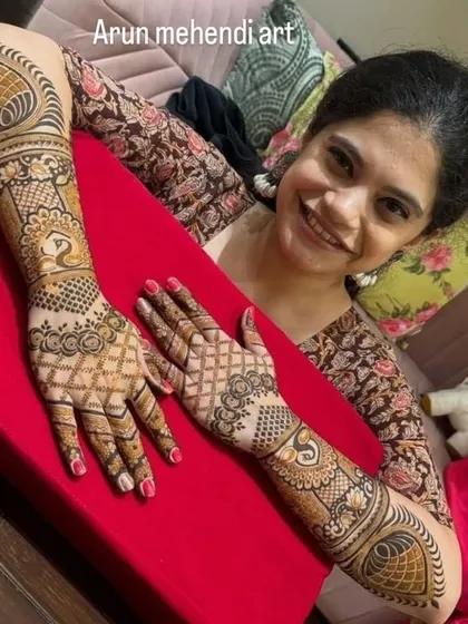 This client is happy with her asymmetrical mehendi design. One arm features a detailed peacock and paisley pattern, while the other has a complementary floral and grid design.