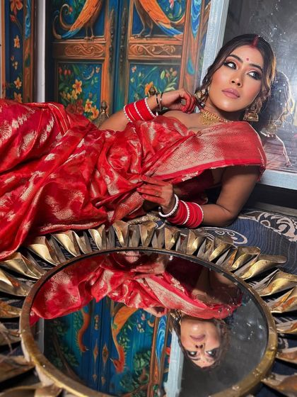 The divine Bengali bride. This look features the traditional red bindi, dramatic eyes, and a beautiful red Banarasi saree.